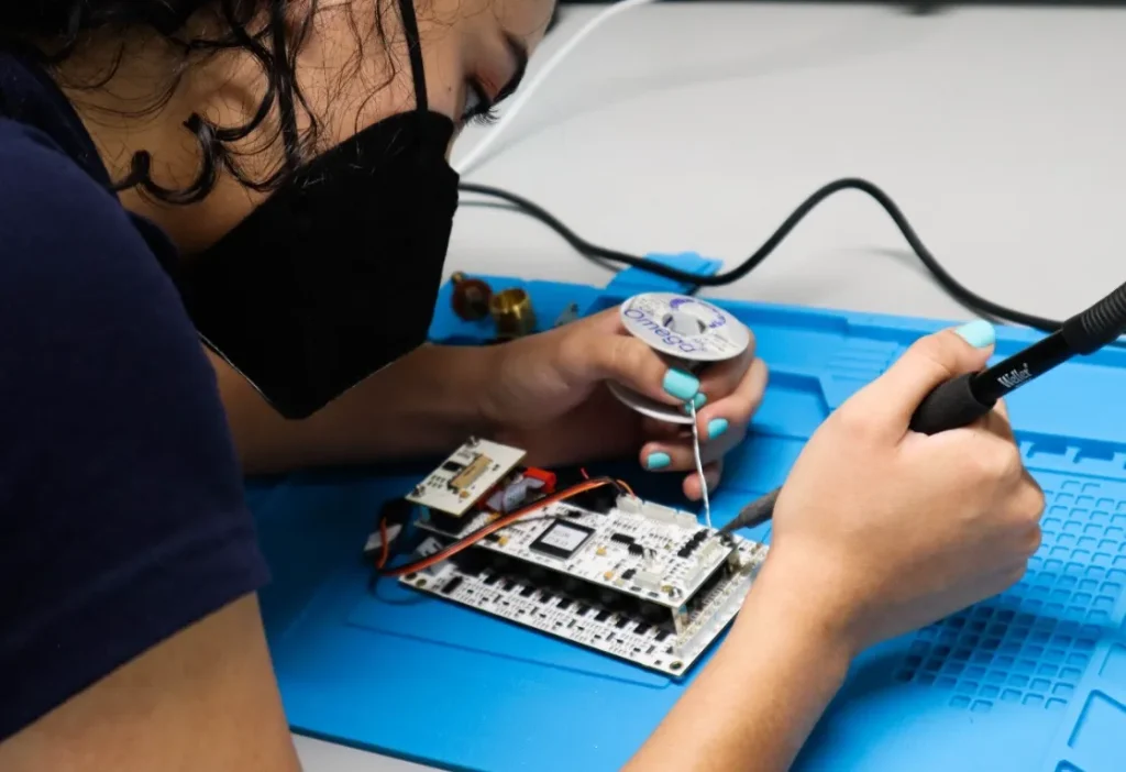 Ingeniera biomédica soldando una pieza de componente electrónico.